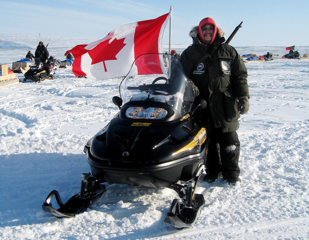 Canadian Inuit ranger stands on the snow next to his snowmobile at Resolute Bay, Canada